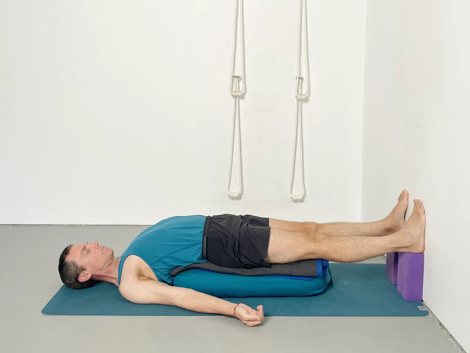 Rod lying on his back over a bolster, with a blanket across his hips and his feet resting on blocks.