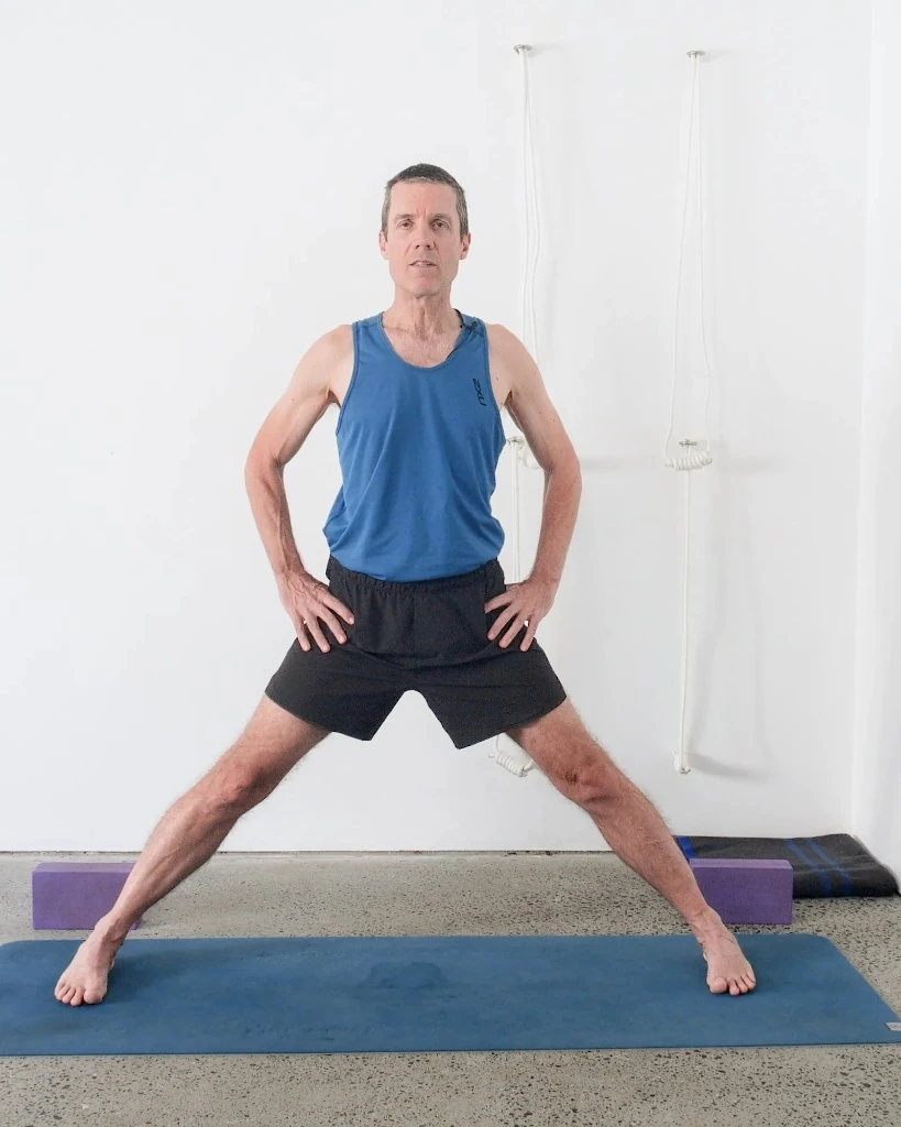 Rod Stennard in the Yoga Selection studio, standing on a mat with wall ropes behind him.