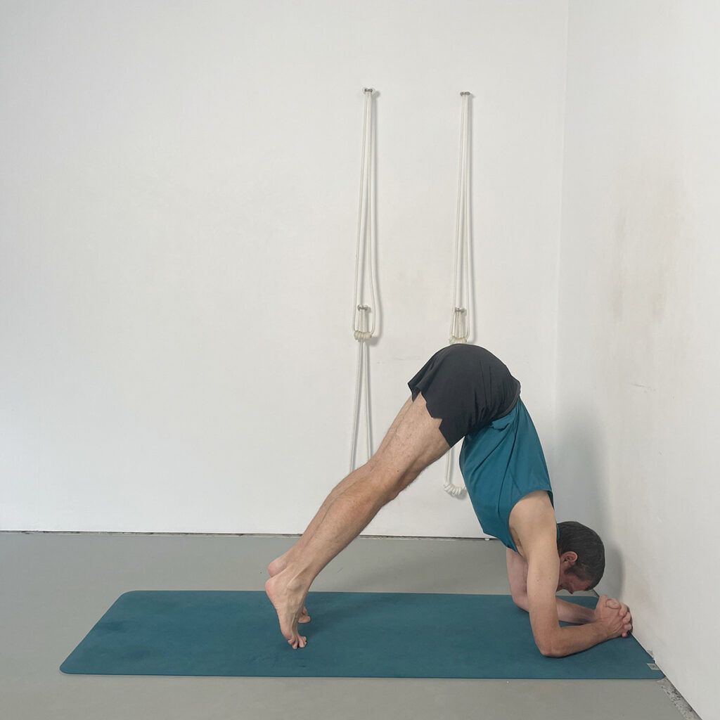 headstand preparation with knuckles to the wall